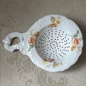 Floral porcelain tea strainer, circa 1920s, with orange and yellow flowers